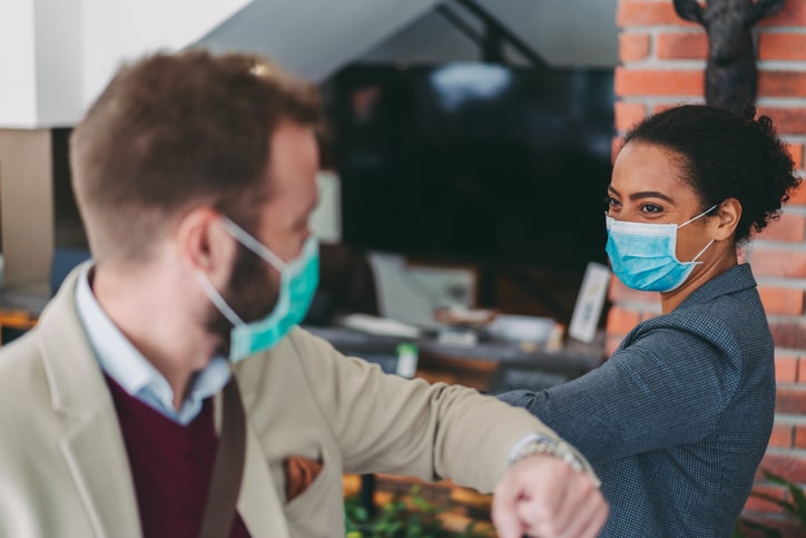 Coworkers in the office practicing alternative greeting to avoid handshakes during COVID-19